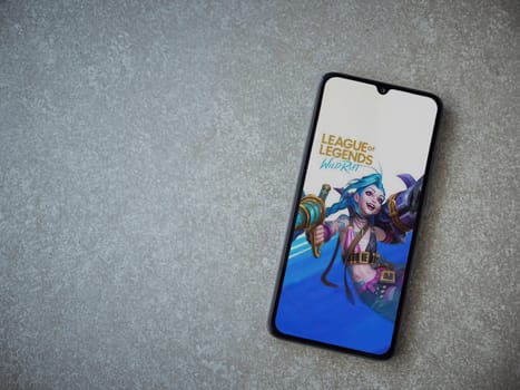 Lod, Israel - July 16,2023: League of Legends - Wild Rift app launch screen on smartphone on ceramic stone background. Top view flat lay with copy space.