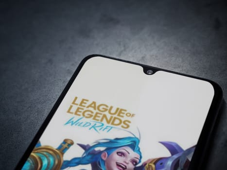Lod, Israel - July 16,2023: League of Legends - Wild Rift app launch screen on smartphone on dark marble stone background. Top view flat lay with copy space.