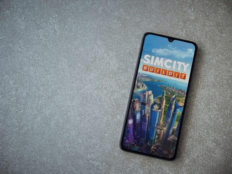 Lod, Israel - July 16,2023: SimCity BuildIt app launch screen on smartphone on ceramic stone background. Top view flat lay with copy space.