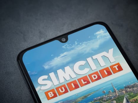 Lod, Israel - July 16,2023: SimCity BuildIt app launch screen on smartphone on dark marble stone background. Top view flat lay with copy space.