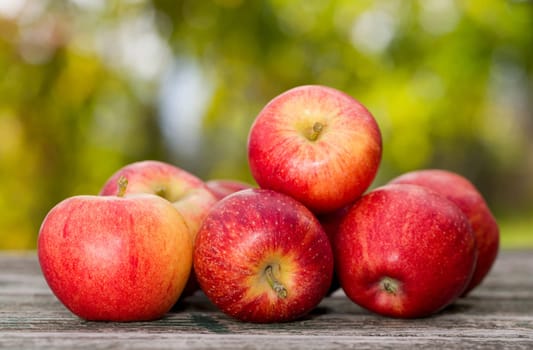 Close-up of few organic red apples on a wooden table.