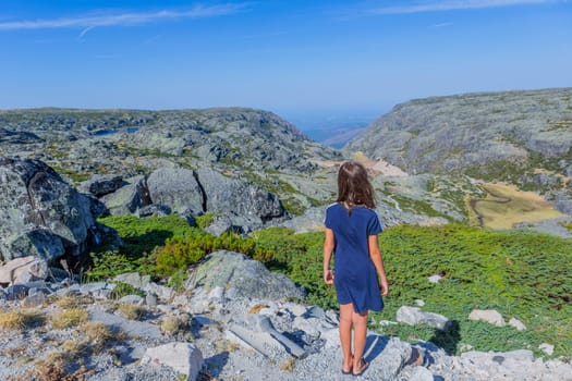 Girl tourist standing overlooking at picturesque view of the mountain, in Serra da Estrela, Portugal. View from behind