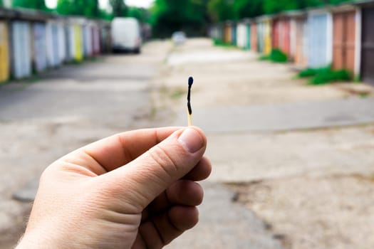 A match, a hand with matches against the background of old garages in city.