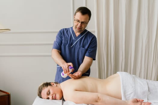 Plump woman getting hot stones arm massage in a spa salon. Therapy, wellness and relaxation concept
