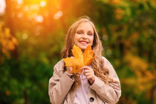 Cute stylish girl with long blonde hair in an autumn park. Autumn kids fashion, lifestyle portrait.