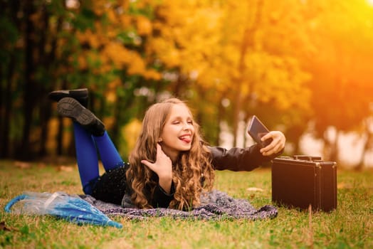 Cute stylish girl with long blonde hair in an autumn park. Autumn kids fashion, lifestyle portrait.