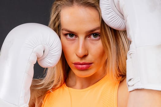 Woman boxer in gloves training on a yellow and dark studio background