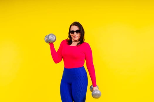 Sporty model with curvy figure with a dumbbells. Dynamic movement. Motivation and healthy lifestyle