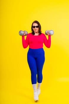Sporty model with curvy figure with a dumbbells. Dynamic movement. Motivation and healthy lifestyle