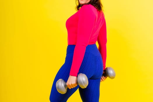 Sporty model with curvy figure with a dumbbells. Dynamic movement. Motivation and healthy lifestyle