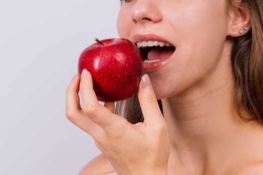 Morning breakfast. Woman with healthy teeth holding apples on a grey isolated background.