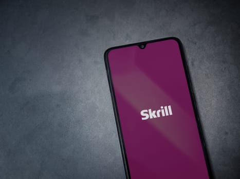 Lod, Israel - July 16,2023: Skrill app launch screen on smartphone on dark marble stone background. Top view flat lay with copy space.