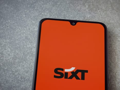 Lod, Israel - July 16,2023: SIXT rent app launch screen on smartphone on ceramic stone background. Top view flat lay with copy space.