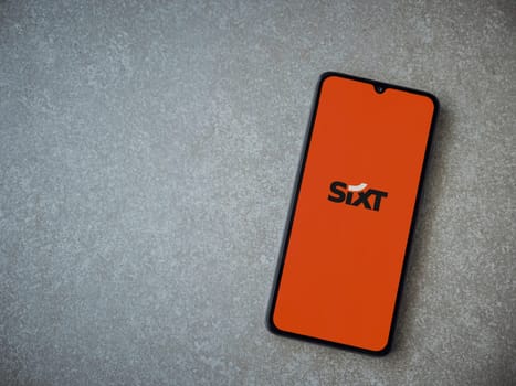 Lod, Israel - July 16,2023: SIXT rent app launch screen on smartphone on ceramic stone background. Top view flat lay with copy space.