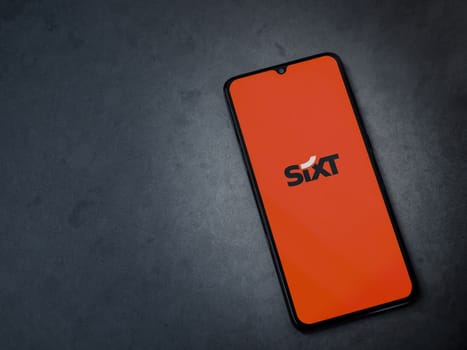 Lod, Israel - July 16,2023: SIXT rent app launch screen on smartphone on dark marble stone background. Top view flat lay with copy space.