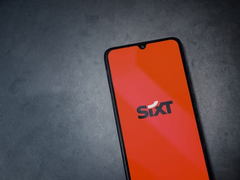 Lod, Israel - July 16,2023: SIXT rent app launch screen on smartphone on dark marble stone background. Top view flat lay with copy space.