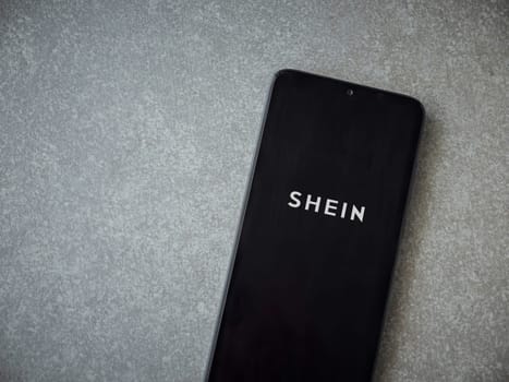 Lod, Israel - July 16,2023: Shein app launch screen on smartphone on ceramic stone background. Top view flat lay with copy space.