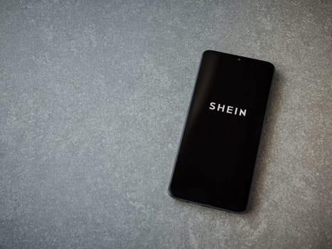 Lod, Israel - July 16,2023: Shein app launch screen on smartphone on ceramic stone background. Top view flat lay with copy space.