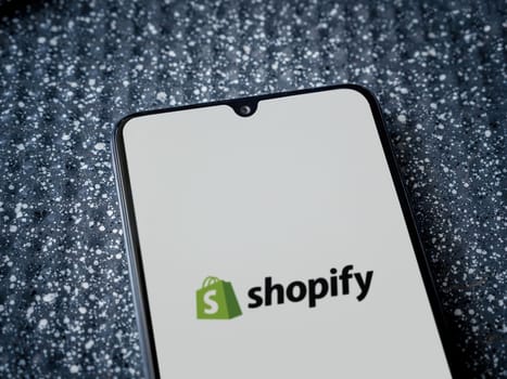 Lod, Israel - July 16,2023: Shopify app launch screen on smartphone on metallic background. Close up top view flat lay.
