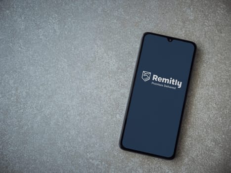 Lod, Israel - July 16,2023: Remitly app launch screen on smartphone on ceramic stone background. Top view flat lay with copy space.