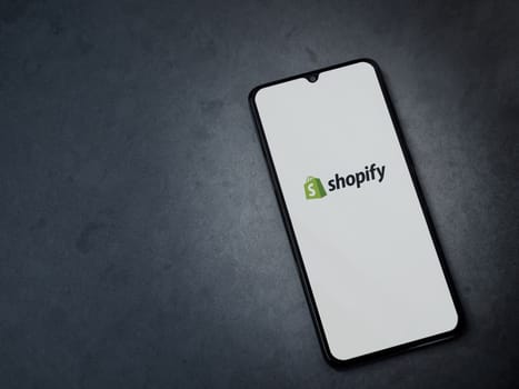 Lod, Israel - July 16,2023: Shopify app launch screen on smartphone on dark marble stone background. Top view flat lay with copy space.