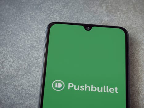 Lod, Israel - July 16,2023: Pushbullet app launch screen on smartphone on ceramic stone background. Top view flat lay with copy space.