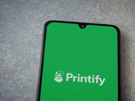 Lod, Israel - July 16,2023: Printify app launch screen on smartphone on ceramic stone background. Top view flat lay with copy space.