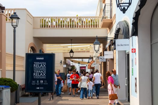 Sicily, Italy, Agira - 30 Sep 2023. Sicilia Outlet Village shopping centre is a popular visitor magnet. Passage with people where shopping at Outlet Village.