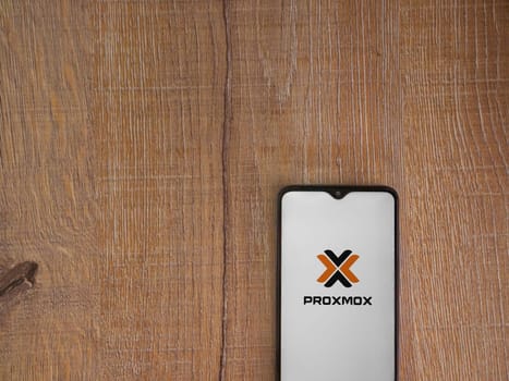 Lod, Israel - July 16,2023: Proxmox Virtual Environment app launch screen on smartphone on wooden background. Top view flat lay with copy space.