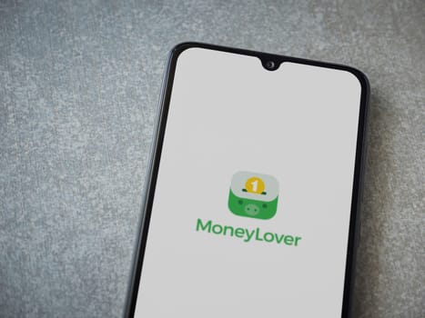 Lod, Israel - July 16,2023: Money Lover app launch screen on smartphone on ceramic stone background. Top view flat lay with copy space.