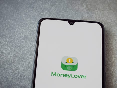 Lod, Israel - July 16,2023: Money Lover app launch screen on smartphone on ceramic stone background. Top view flat lay with copy space.