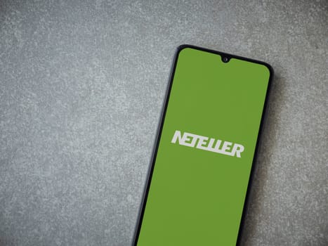 Lod, Israel - July 16,2023: NETELLER app launch screen on smartphone on ceramic stone background. Top view flat lay with copy space.