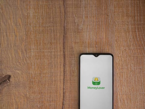 Lod, Israel - July 16,2023: Money Lover app launch screen on smartphone on wooden background. Top view flat lay with copy space.