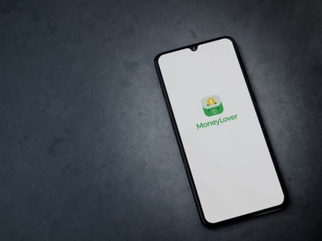 Lod, Israel - July 16,2023: Money Lover app launch screen on smartphone on dark marble stone background. Top view flat lay with copy space.