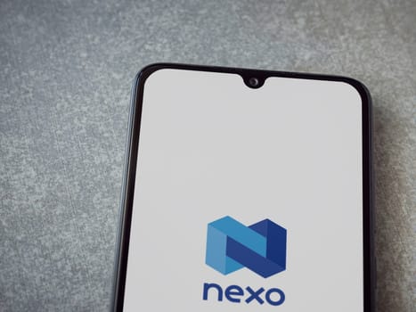 Lod, Israel - July 16,2023: Nexo app launch screen on smartphone on ceramic stone background. Top view flat lay with copy space.