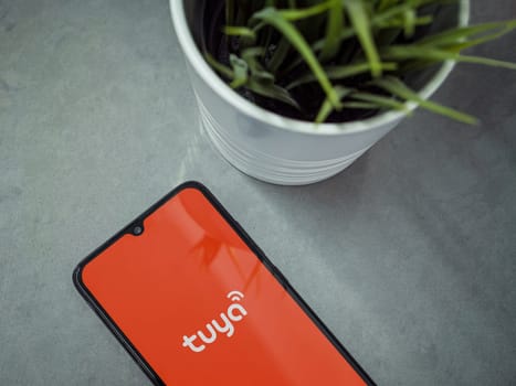 Lod, Israel - July 16,2023: Modern workspace with smartphone with Tuya Smart app launch screen on marble background. Close up top view flat lay.