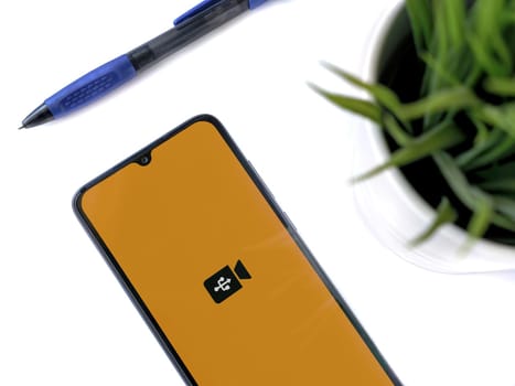 Lod, Israel - July 16,2023: Modern workspace with smartphone with USB Camera app launch screen on white background. Close up top view flat lay.