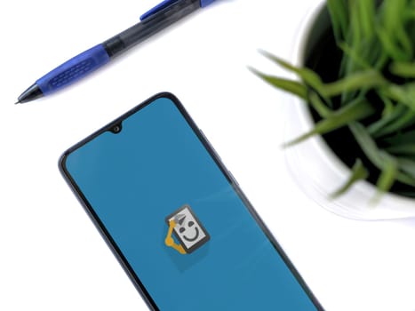 Lod, Israel - July 16,2023: Modern workspace with smartphone with Automate app launch screen on white background. Close up top view flat lay.