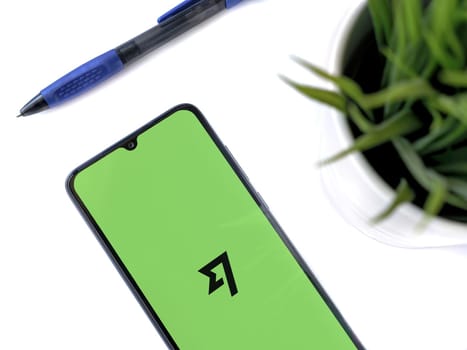 Lod, Israel - July 16,2023: Modern workspace with smartphone with Wise app launch screen on white background. Close up top view flat lay.