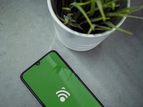 Lod, Israel - July 16,2023: Modern workspace with smartphone with Unified Remote app launch screen on marble background. Close up top view flat lay.