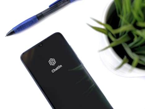 Lod, Israel - July 16,2023: Modern workspace with smartphone with ChatOn app launch screen on white background. Close up top view flat lay.