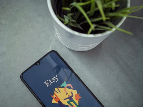 Lod, Israel - July 16,2023: Modern workspace with smartphone with Etsy Seller app launch screen on marble background. Close up top view flat lay.