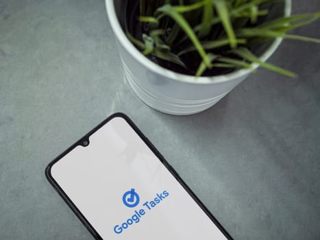 Lod, Israel - July 16,2023: Modern workspace with smartphone with Google Task app launch screen on marble background. Close up top view flat lay.