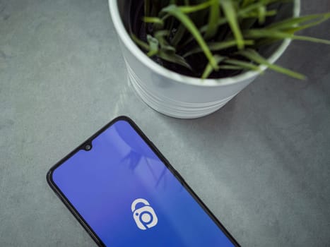 Lod, Israel - July 16,2023: Modern workspace with smartphone with IDrive Photo Backup app launch screen on marble background. Close up top view flat lay.