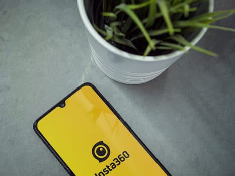 Lod, Israel - July 16,2023: Modern workspace with smartphone with Insta360 app launch screen on marble background. Close up top view flat lay.