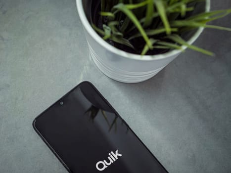 Lod, Israel - July 16,2023: Modern workspace with smartphone with GoPro Quik - Video Editor app launch screen on marble background. Close up top view flat lay.