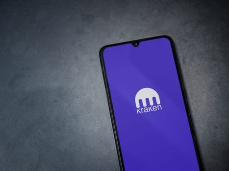 Lod, Israel - July 16,2023: Kraken app launch screen on smartphone on dark marble stone background. Top view flat lay with copy space.