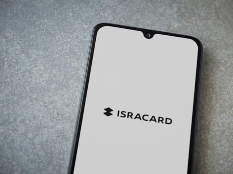 Lod, Israel - July 16,2023: Isracard app launch screen on smartphone on ceramic stone background. Top view flat lay with copy space.