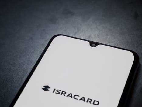 Lod, Israel - July 16,2023: Isracard app launch screen on smartphone on dark marble stone background. Top view flat lay with copy space.