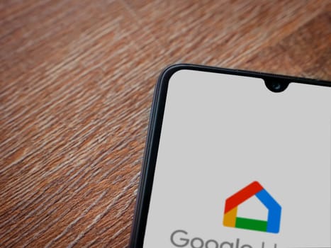 Lod, Israel - July 16,2023: Google Home app launch screen on smartphone on wooden background. Top view flat lay with copy space.